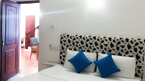 A bedroom with a bed, a headboard with a cow print pattern, and a door leading to another room. - C J Beach Resort (Uswetakeiyawa)