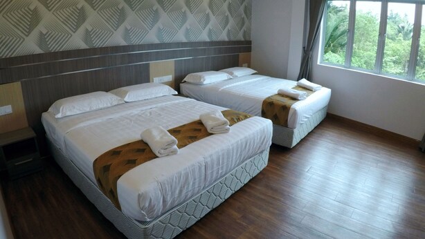 Habitación de hotel con dos camas, papel tapiz estampado, un ventanal con vistas y suelo de madera.