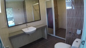 Un baño con lavamanos, espejo, inodoro y zona de ducha.