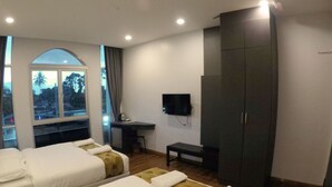 Una habitación de hotel con dos camas, un escritorio, un televisor y un armario.
