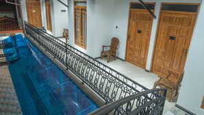 A multi-level building with a glass-enclosed swimming pool, wooden doors, and a metal railing.