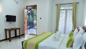 A hotel room with a bed, a TV, a wooden table, and a balcony with a spiral staircase.