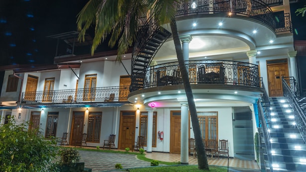 A multi-story hotel with a central staircase, balconies, and a well-lit entrance.