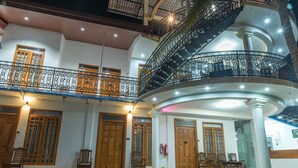A multi-story building with a central spiral staircase, wooden doors, and a balcony with wrought iron railings.