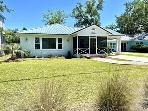 A single-story house with a covered porch, a small front yard, and a clear blue sky.