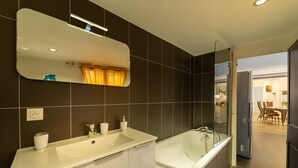 Un baño moderno con un espejo grande, dos lavamanos y una bañera.