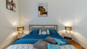 Un dormitorio con una cama, dos mesitas de noche y dos lámparas de pared.