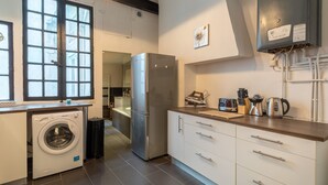 Una cocina compacta con lavadora, refrigerador y una encimera con utensilios de cocina.