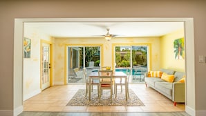 A spacious living area with a dining table, chairs, a sofa, and a ceiling fan.