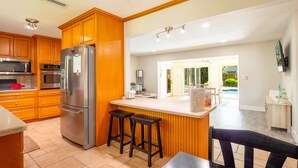 A modern kitchen with wooden cabinets, stainless steel appliances, and a bar area.