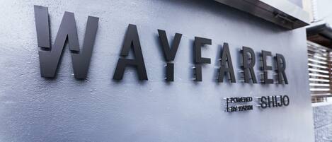 A sign with the name "WAYFARE" and the text "EPOWENED BY SHIKO" on a textured wall.