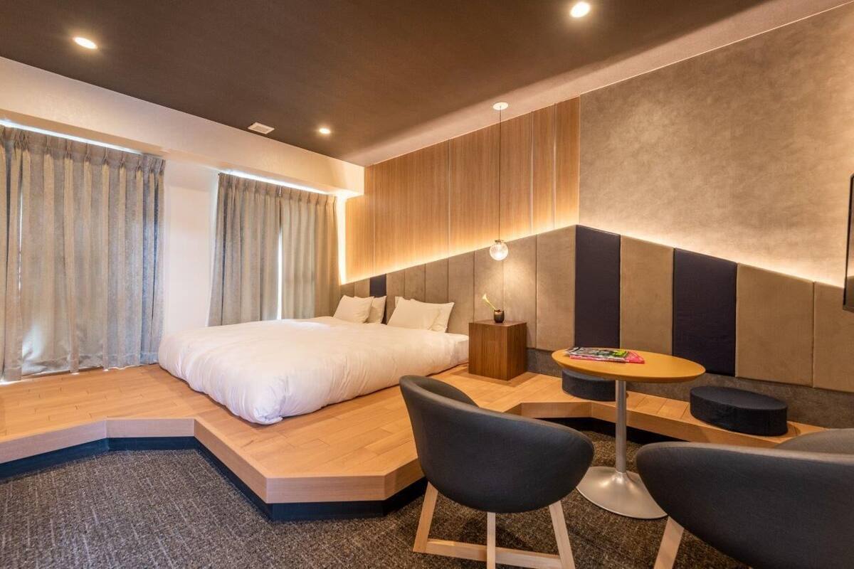 Ein modernes Hotelzimmer mit einem Bett, einem kleinen Tisch mit Stühlen und einer fest installierten Sitzbank.