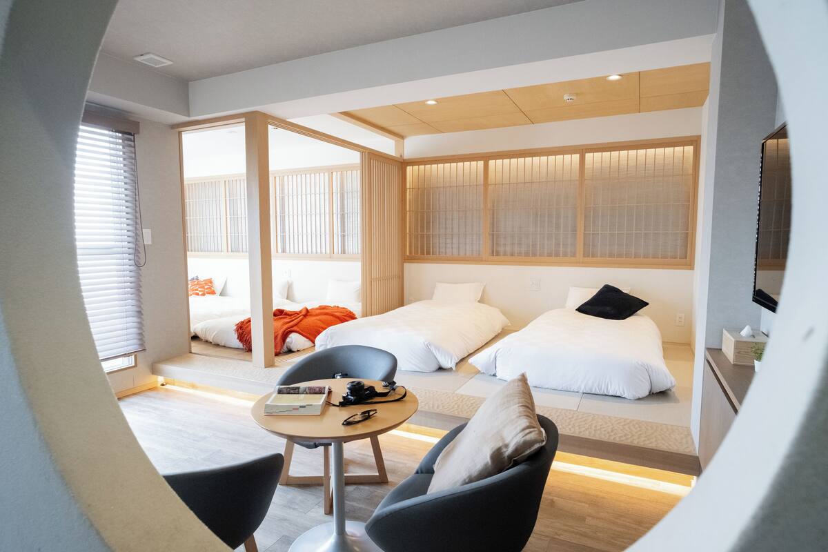 Ein modernes Hotelzimmer mit zwei Betten, einer Essecke und Blick ins Freie.