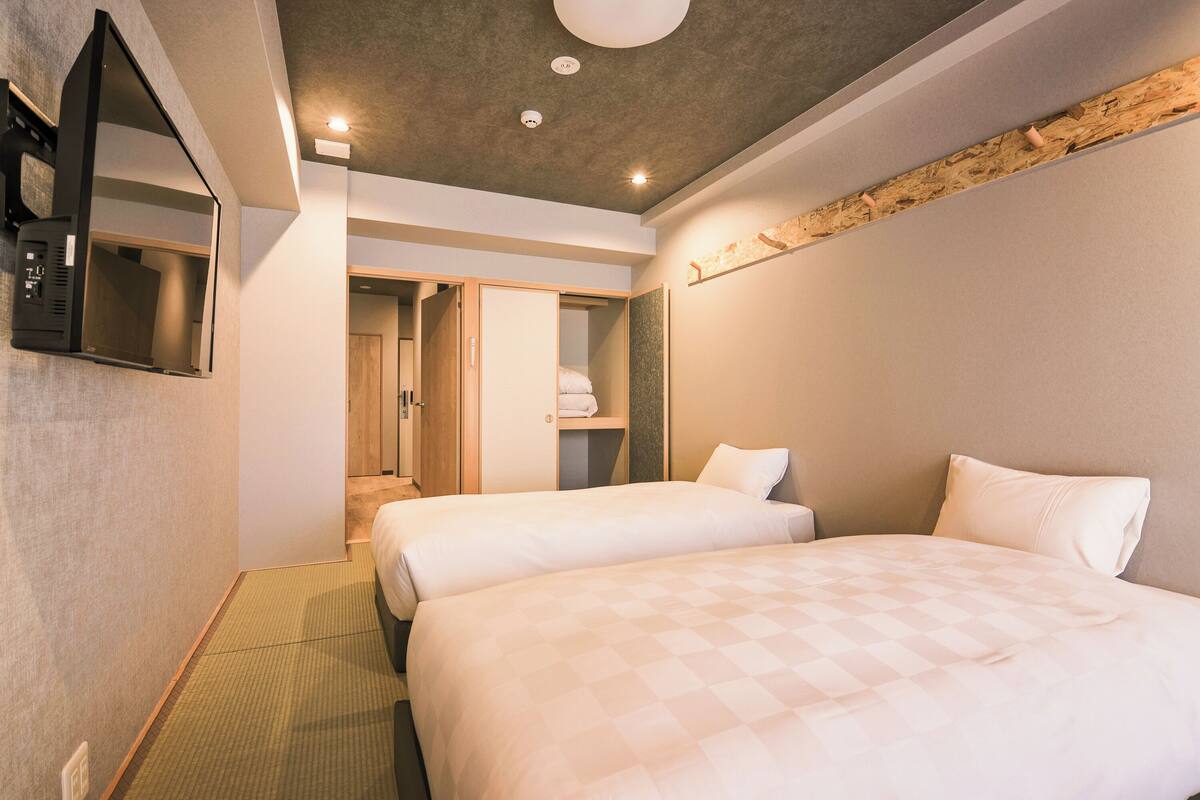 Ein Hotelzimmer mit zwei Betten, einem Flachbildfernseher und einem Holzbalken-Eingang.