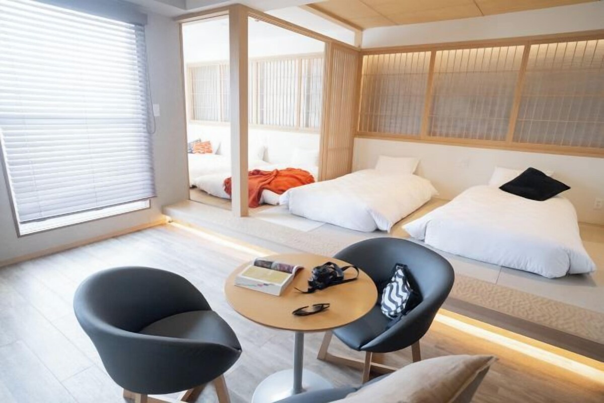 A hotel room with two beds, a small round table, and two black chairs.