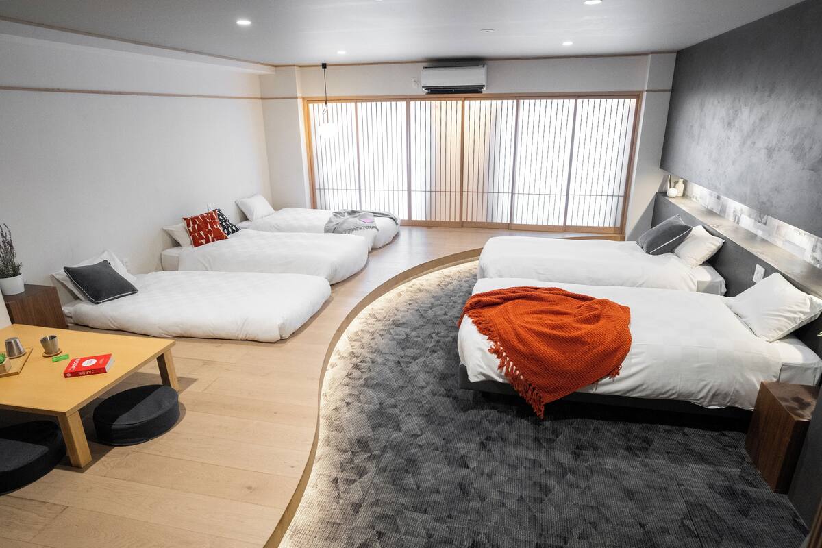 Ein modernes Hotelzimmer mit einem bogenförmigen Bett, einem kleinen Tisch und Blick durch große Schiebetüren nach draußen.