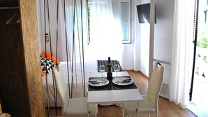Un coin repas avec une table dressée pour deux personnes, une bouteille de vin et deux verres. On aperçoit, à l'arrière-plan, un lit avec un oreiller noir et blanc.