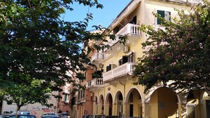 Une rue bordée de voitures garées et un immeuble doté d’un balcon.