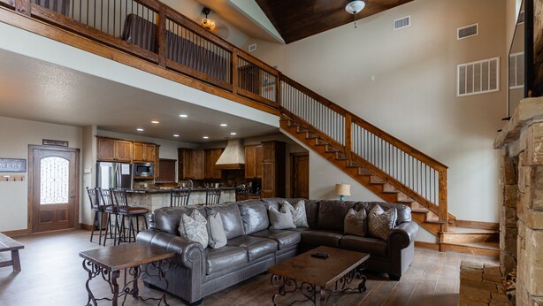 A spacious living room with a leather sectional sofa, a wooden dining table, and a kitchen in the background. - Soak up the Sun and Golf Course Views from The Sweet Spot! (Concan)