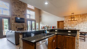 A modern kitchen with a stone backsplash, wooden cabinets, and a built-in dishwasher. - Soak up the Sun and Golf Course Views from The Sweet Spot! (Concan)