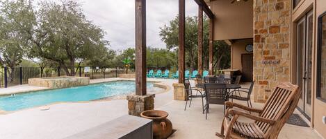 A covered outdoor area with a pool, seating, and a stone wall.