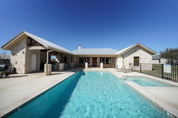 A two-story stone building with a swimming pool in front.