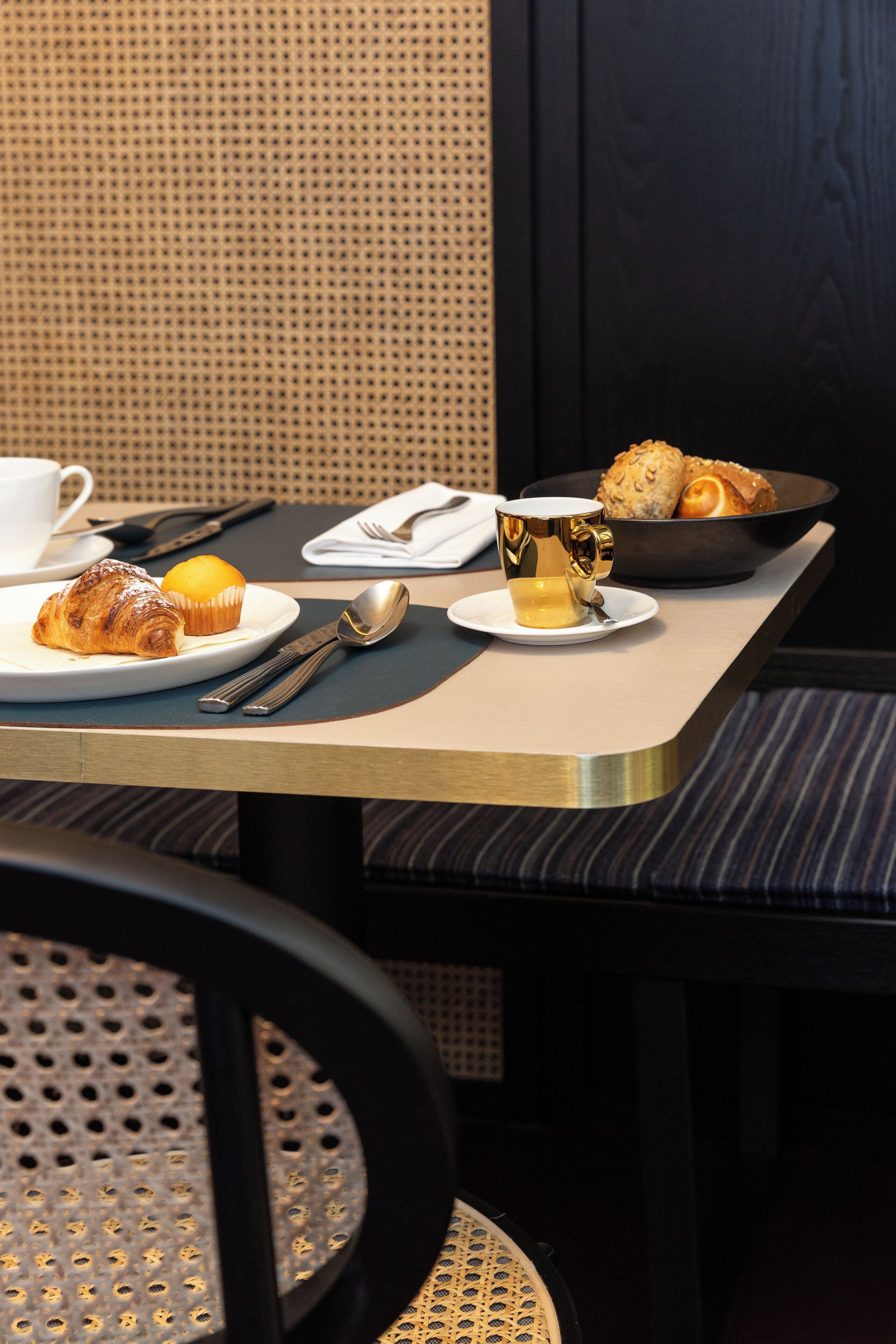 Une table de petit-déjeuner avec des croissants, des muffins et une tasse de café.