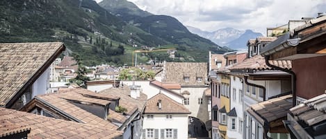 Eine enge Straße, gesäumt von Gebäuden, mit blauem Himmel und Bergen im Hintergrund.