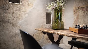 Une table rustique ornée d’un vase de fleurs et d’un jeu d’échecs.