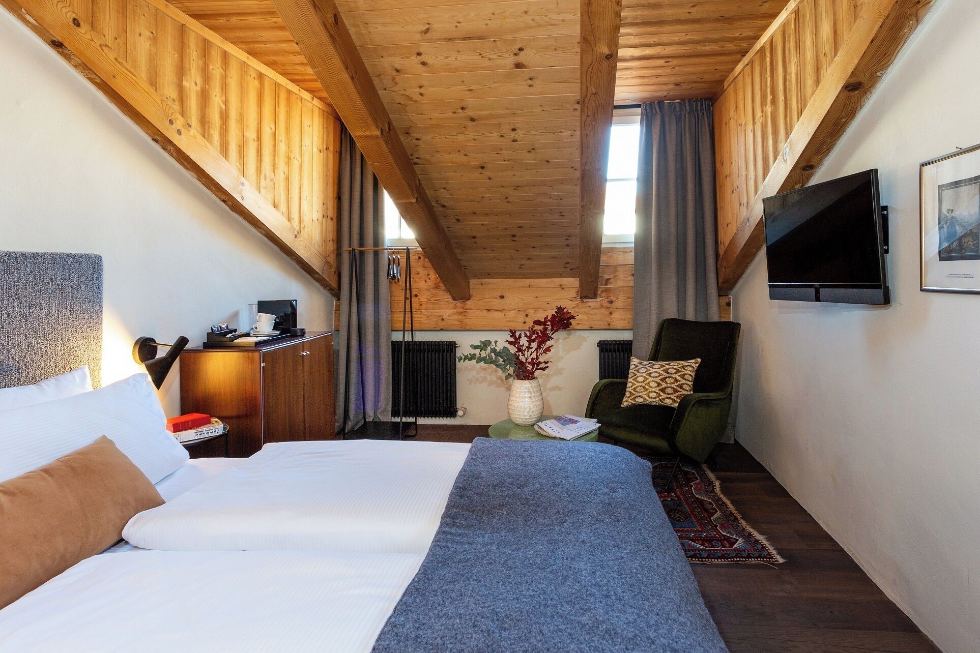 Habitación de hotel con una cama, un escritorio, una silla, un televisor y una ventana.