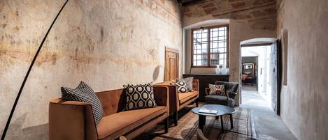 Une pièce chaleureuse avec un canapé en cuir marron, des coussins à motifs, une petite table ronde et un lampadaire.