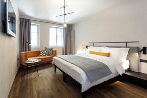 A modern hotel room with a large bed, a sofa, a small table, and a TV mounted on the wall. - Goldenstern Townhouse (Bolzano)