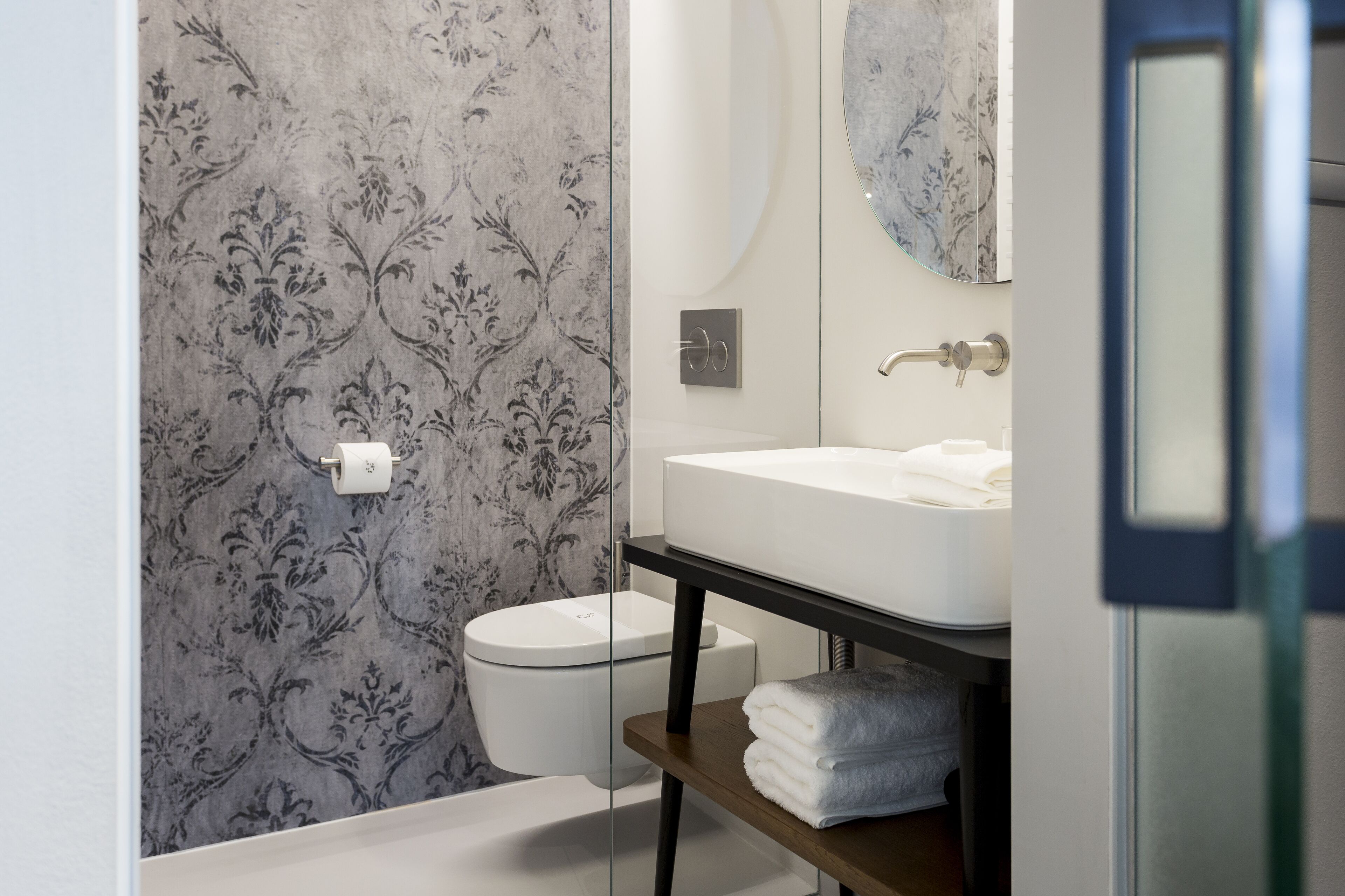 Un baño moderno con inodoro, lavamanos y espejo.