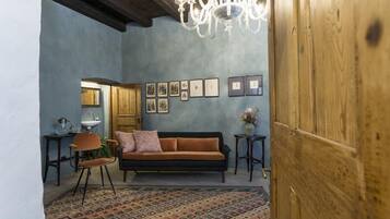 Uma sala de estar aconchegante com um sofá de madeira, um tapete estampado e um candelabro.