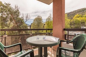 A balcony with a round table and two chairs, overlooking a scenic landscape with trees and hills. - 200m from resort center, 3rd floor, view mountain, balcony, tv, 38m², Serre Chevalier (Briançon)