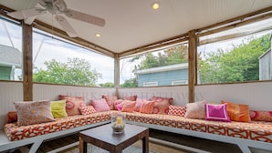 A covered patio with a cushioned bench, a table with candles, and a view of the surrounding area.