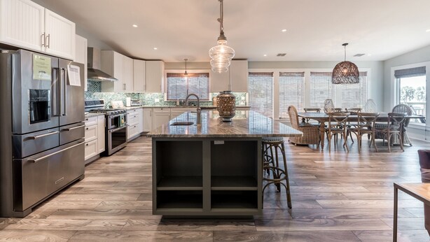 Una cocina moderna con electrodomésticos de acero inoxidable, una isla central y un comedor con sillas de mimbre.