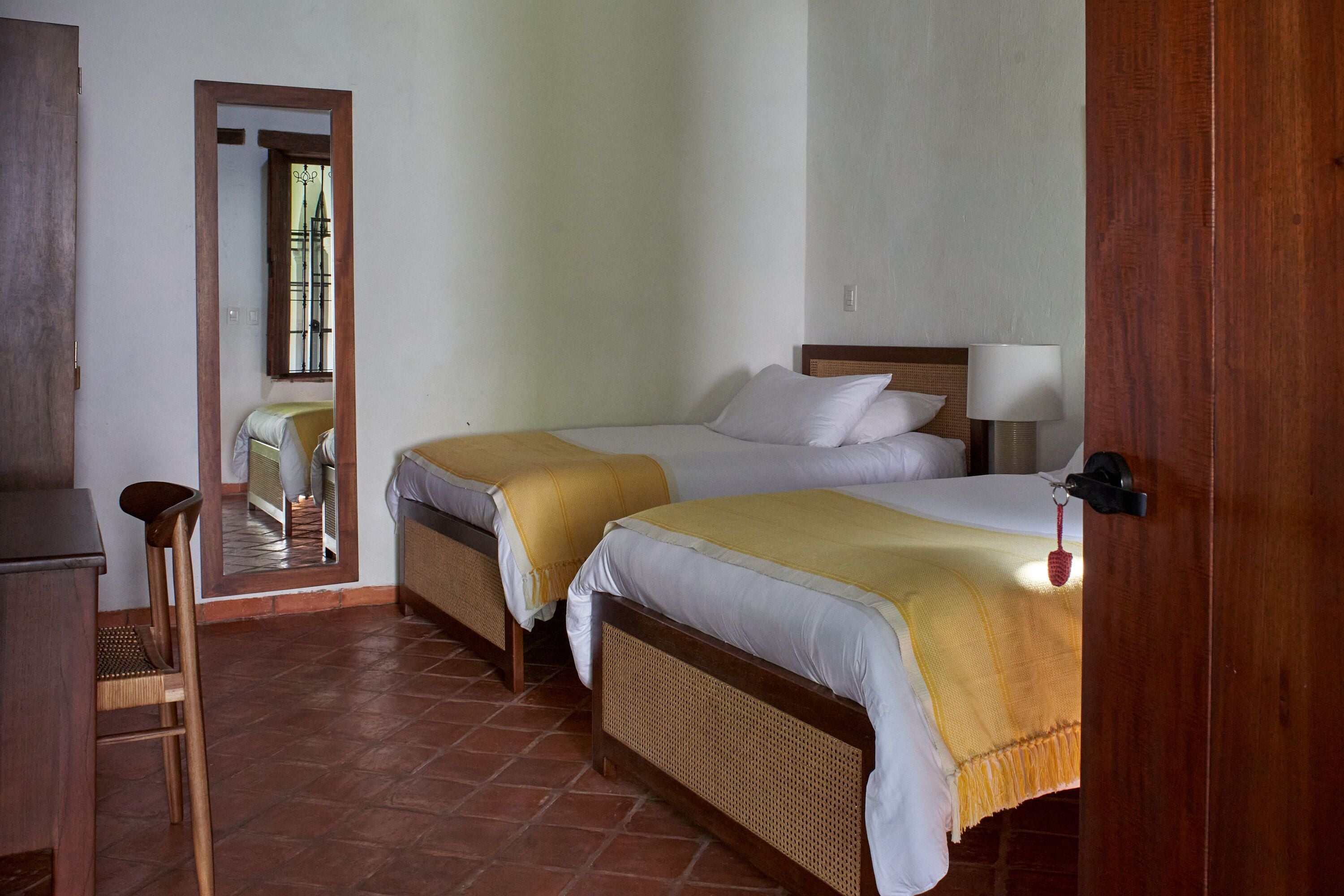 A room with two beds, a wooden desk, and a chair.