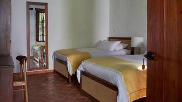 A room with two beds, a wooden desk, and a chair.