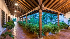 A covered corridor with wooden beams and potted plants.