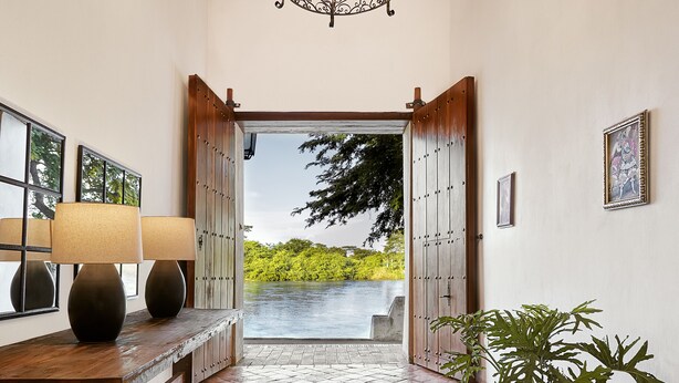 A hallway with a wooden bench, a potted plant, and a view of a lake.