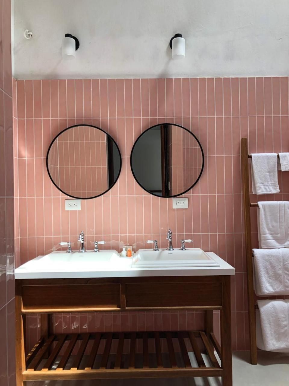 A bathroom with two round mirrors, a white sink, and a wooden vanity.