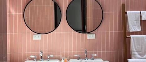 A bathroom with two round mirrors, a white sink, and a wooden vanity.