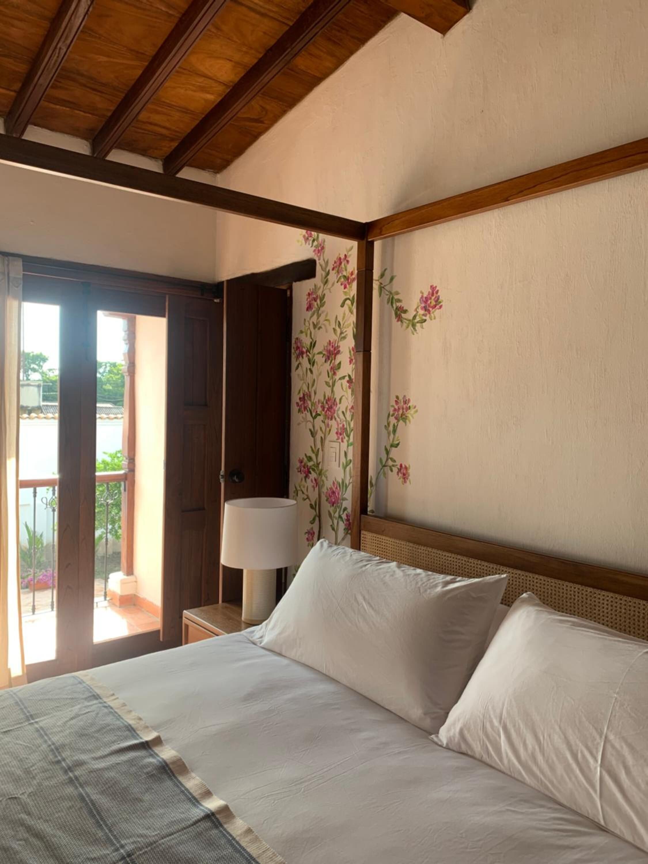Un dormitorio con cama, mesita de noche, lámpara y puerta que da a un espacio exterior.