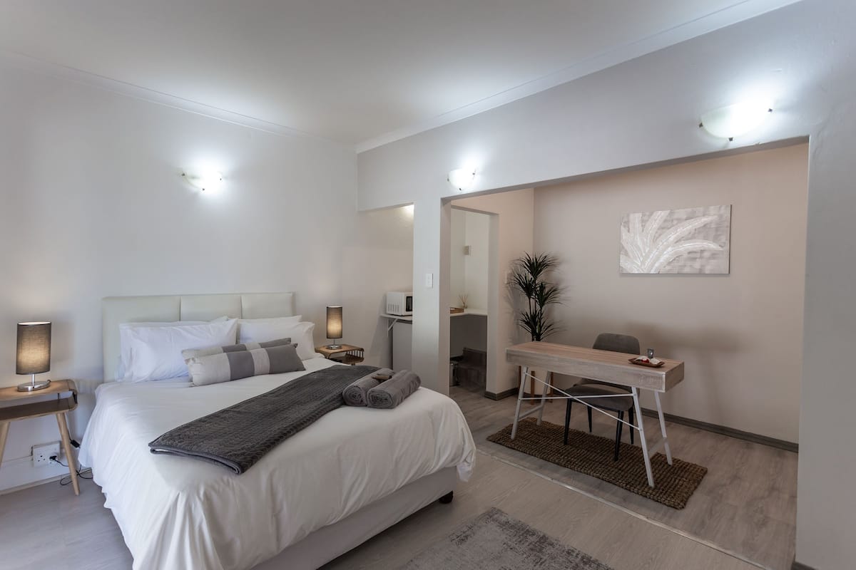 A modern hotel room with a large bed, bedside tables, a desk, and a chair.