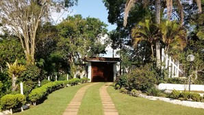 Un chemin menant à un bâtiment entouré d’une végétation luxuriante et d’arbres.
