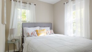 A bedroom with a bed, a bedside table, a lamp, and sheer curtains. - White House on a Hill (Ann Arbor)