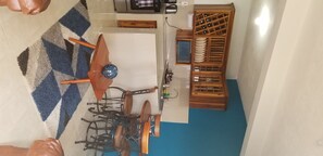 A kitchen with a blue and white patterned rug, a wooden table with a blue bowl, and a wine rack with plates.