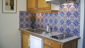 Une cuisine avec des meubles en bois, un évier en acier inoxydable, une cuisinière encastrée et des carreaux décoratifs sur le mur derrière l’évier.
