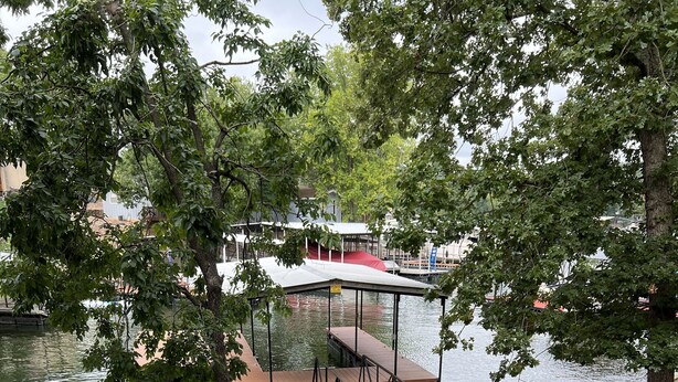 Una terraza junto al lago con una parrilla, un muelle y una zona cubierta.